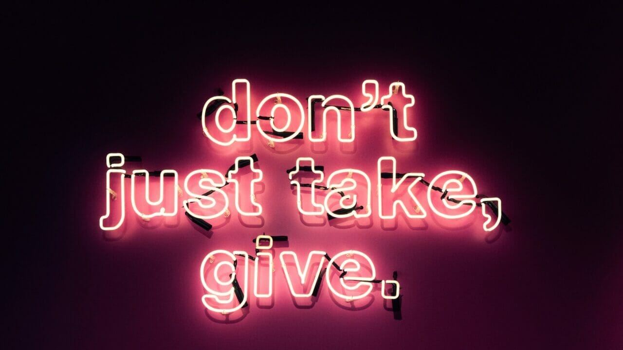 neon sign saying "don't just take, give"